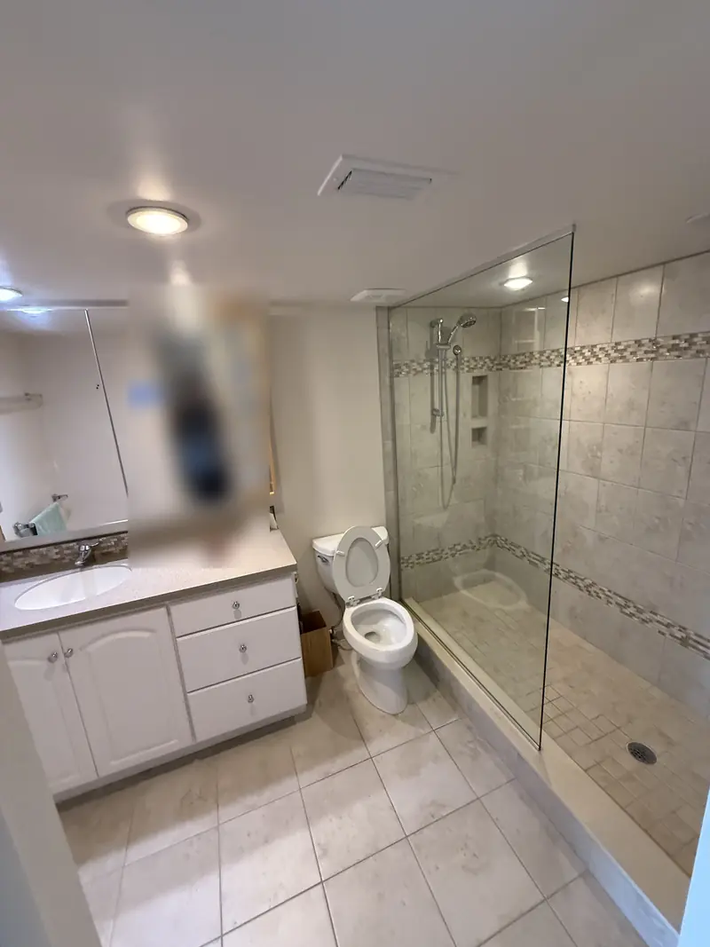 Before: Beige tile bathroom with older vanity and glass shower before the remodel in Sarasota, FL