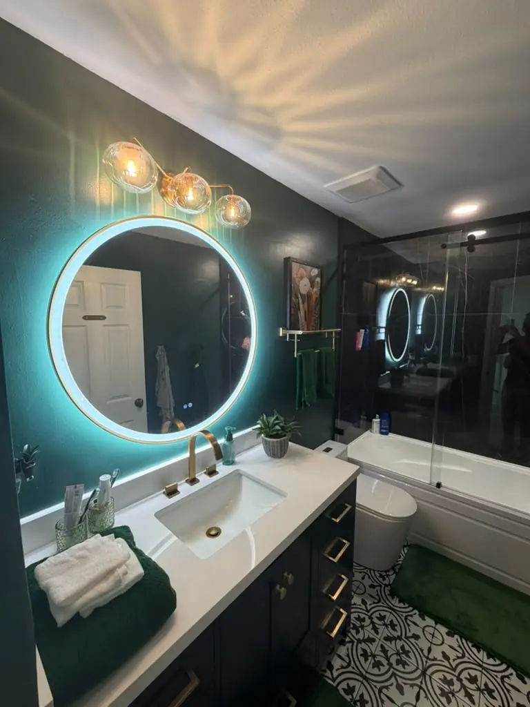 Bathroom vanity with backlit round mirror, gold faucet and quartz top in a Palm Harbor remodel