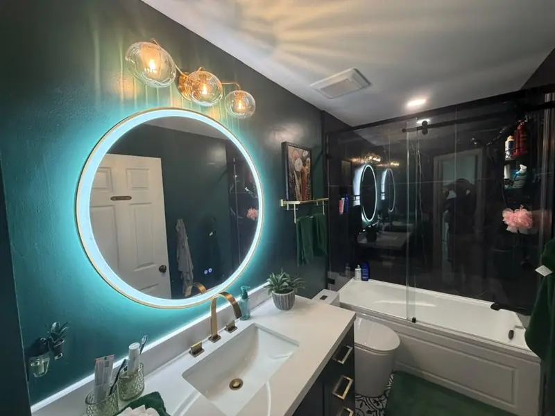 Remodeled bathroom with sliding glass tub enclosure, LED mirror and green accent wall in Palm Harbor