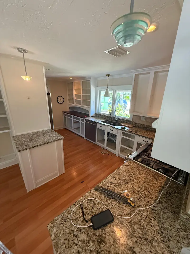 Before: Dated kitchen with granite counters and empty cabinet boxes before the remodel in Sarasota, FL