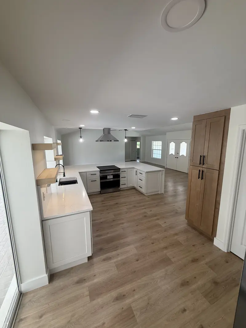 Open kitchen with wood shaker cabinets, white waterfall countertop and new luxury vinyl plank floors in Osprey