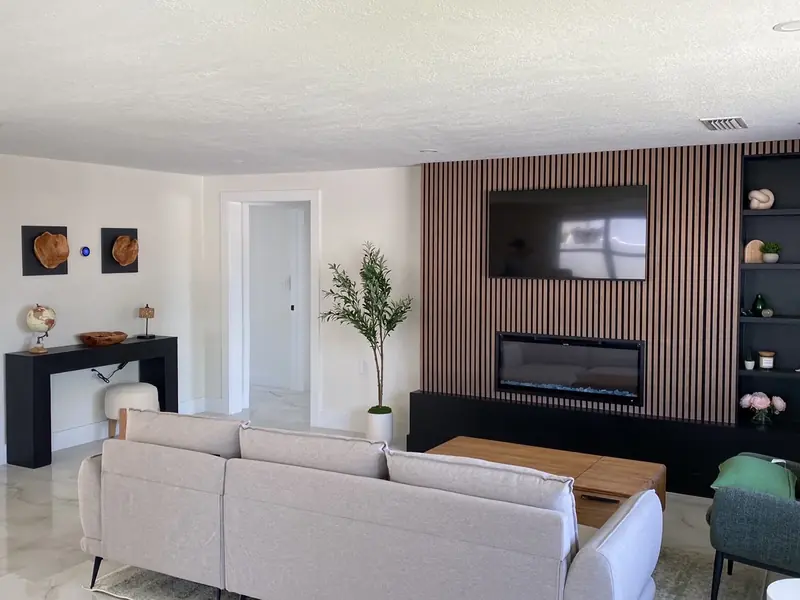 Living room renovation with wood slat accent wall, built-in electric fireplace and shelving in Holmes Beach, FL