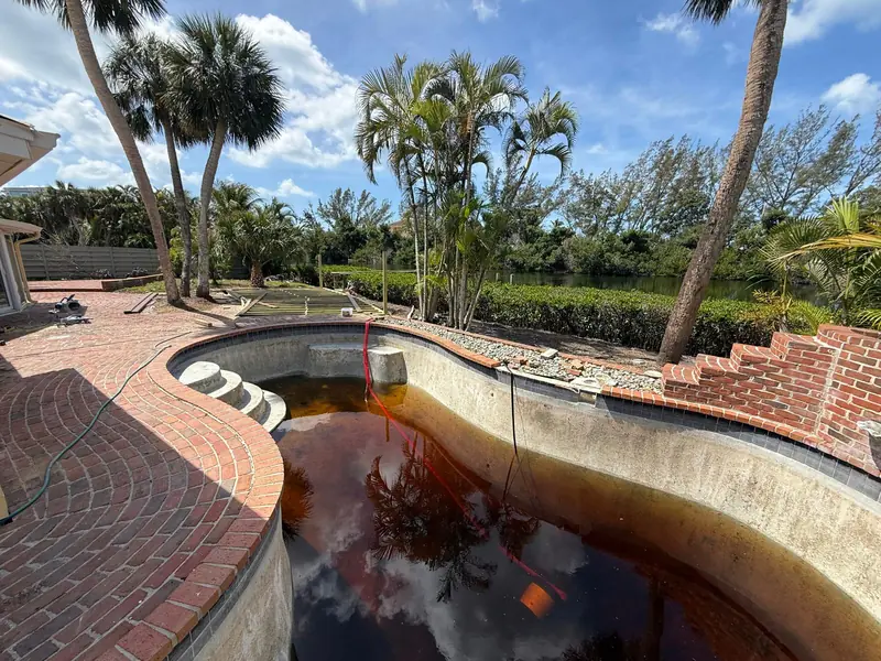 Before: Drained pool with stained shell and brick deck before resurfacing in Siesta Key, FL