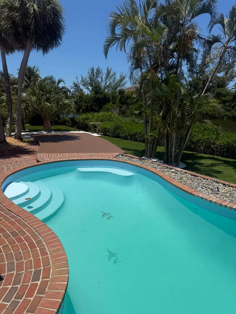 After: Resurfaced pool with fresh turquoise finish and brick deck surrounded by palms in Siesta Key, FL